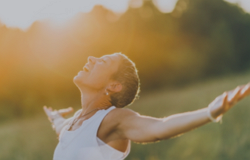 Women, arms outstretched, looking above, connecting with nature and the sun