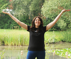 Picture of Rebecca Bishop with her arms in the air with a big smile with a background of trees