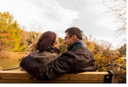 a couple in love sitting on a bench, looking at each other