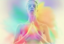 woman with hands in front in a prayer position surrounded by an aura of many beautiful colours