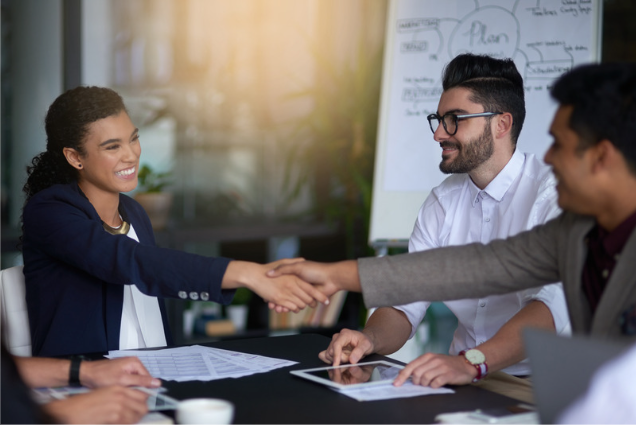 Two work colleagues in a meeting smiling, shaking hands, showing conflict resolution, and harmony, having resolved a stress-free situation