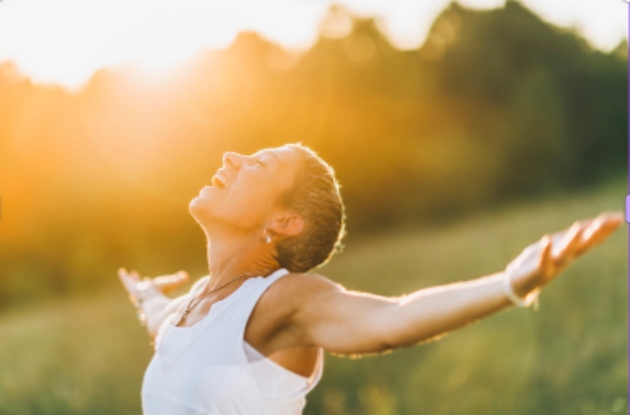 Lady looking up with arms stretched out having let go of disassociation to her trauma, showing she is free